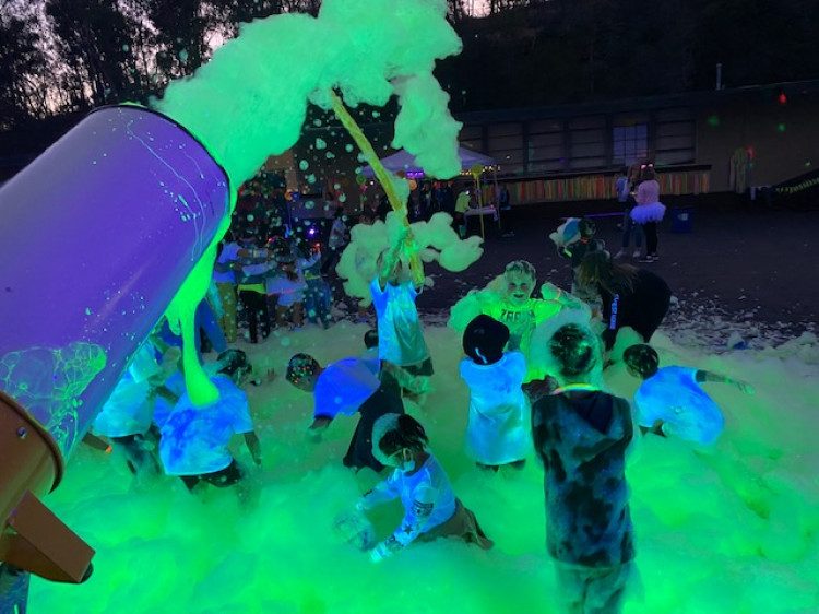 Foam cannon blasting glowing green foam at a school night event