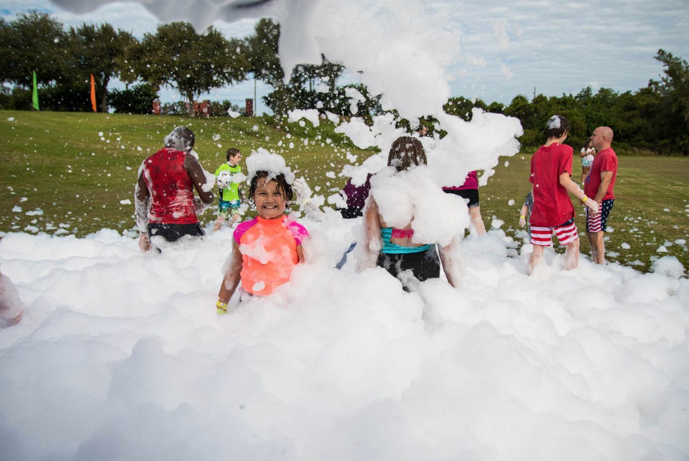 Community foam event at a park with a crowd of guests